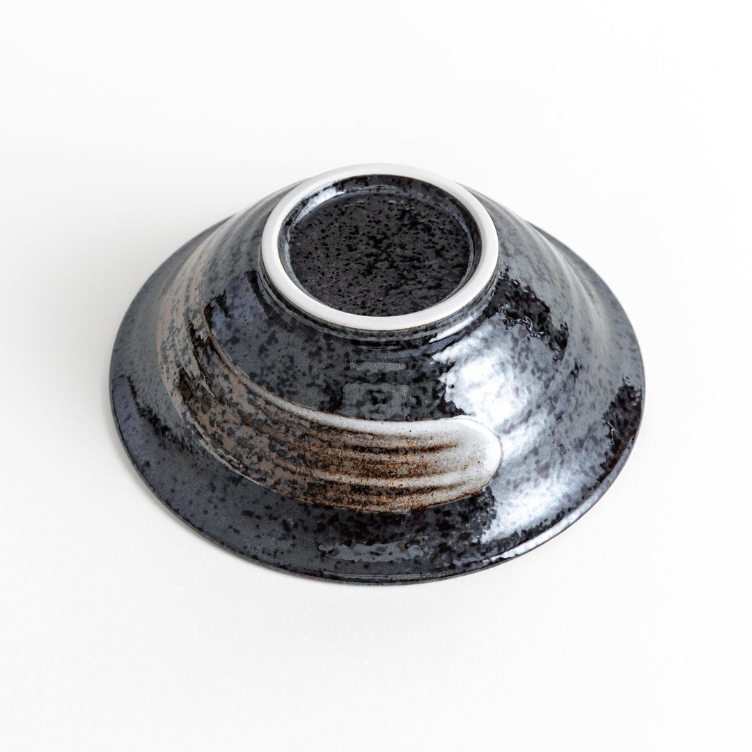 A deep ceramic bowl with a glossy black glaze and irregular brown and speckles.