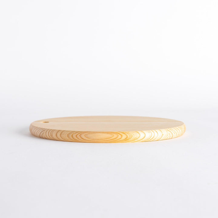 Side view of a round Hinoki cutting board showing its thickness and hole.