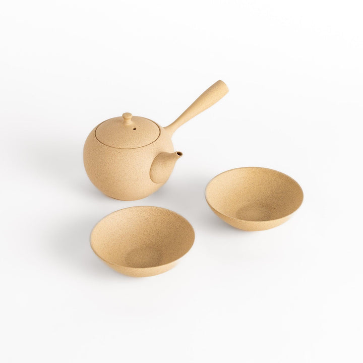 Elegant beige tea set featuring a round teapot with handle and spout, accompanied by matching round bowls, perfect for a serene tea experience.