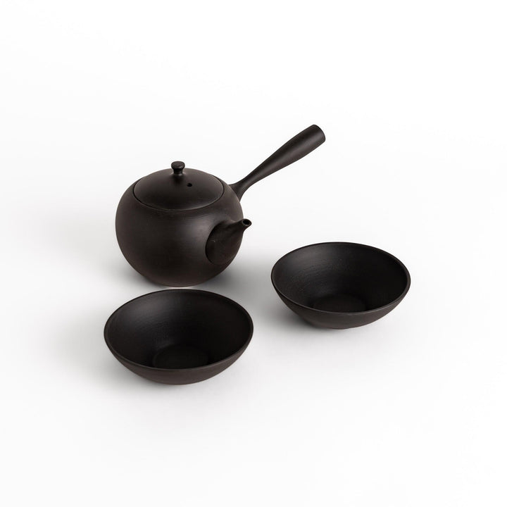 Elegant black tea set featuring a round teapot with a handle and spout, accompanied by matching round bowls, perfect for a serene tea experience.
