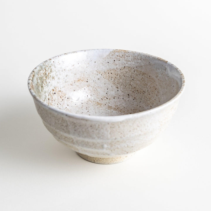 A ceramic bowl with a speckled cream and brown glaze, showcasing an earthy and organic finish.
