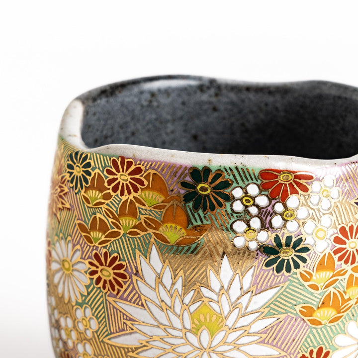 Gray ceramic mug with a vibrant floral pattern in gold and pastel colors, featuring a comfortable handle and a unique speckled glaze.