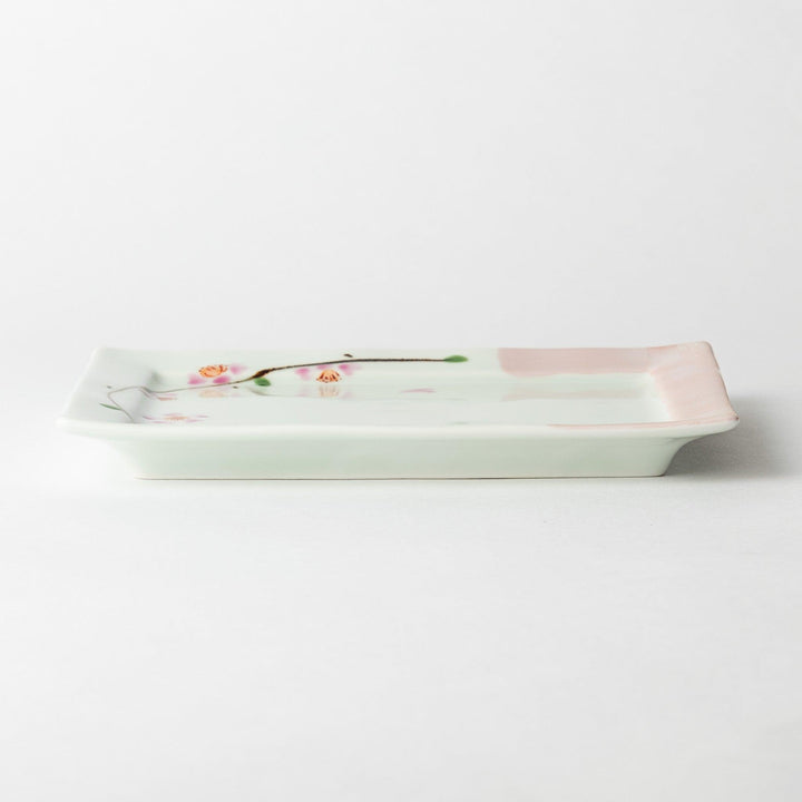 Dessert plate viewed from the side, displaying the square shape and soft pink border with floral details.