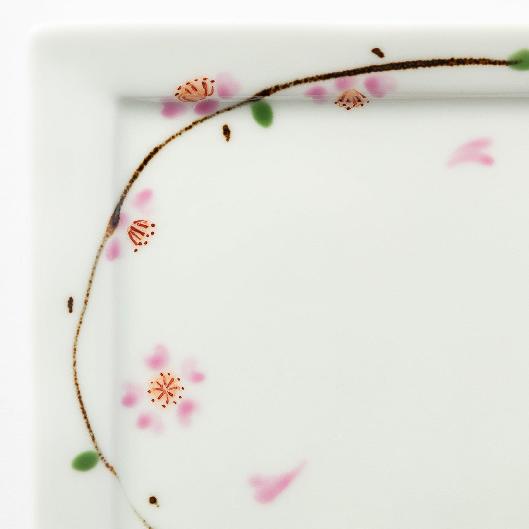 Close-up of the cherry blossom pattern on the dessert plate, focusing on the soft pink petals and green leaves.