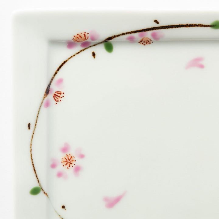 Close-up of the cherry blossom pattern on the dessert plate, focusing on the soft pink petals and green leaves.