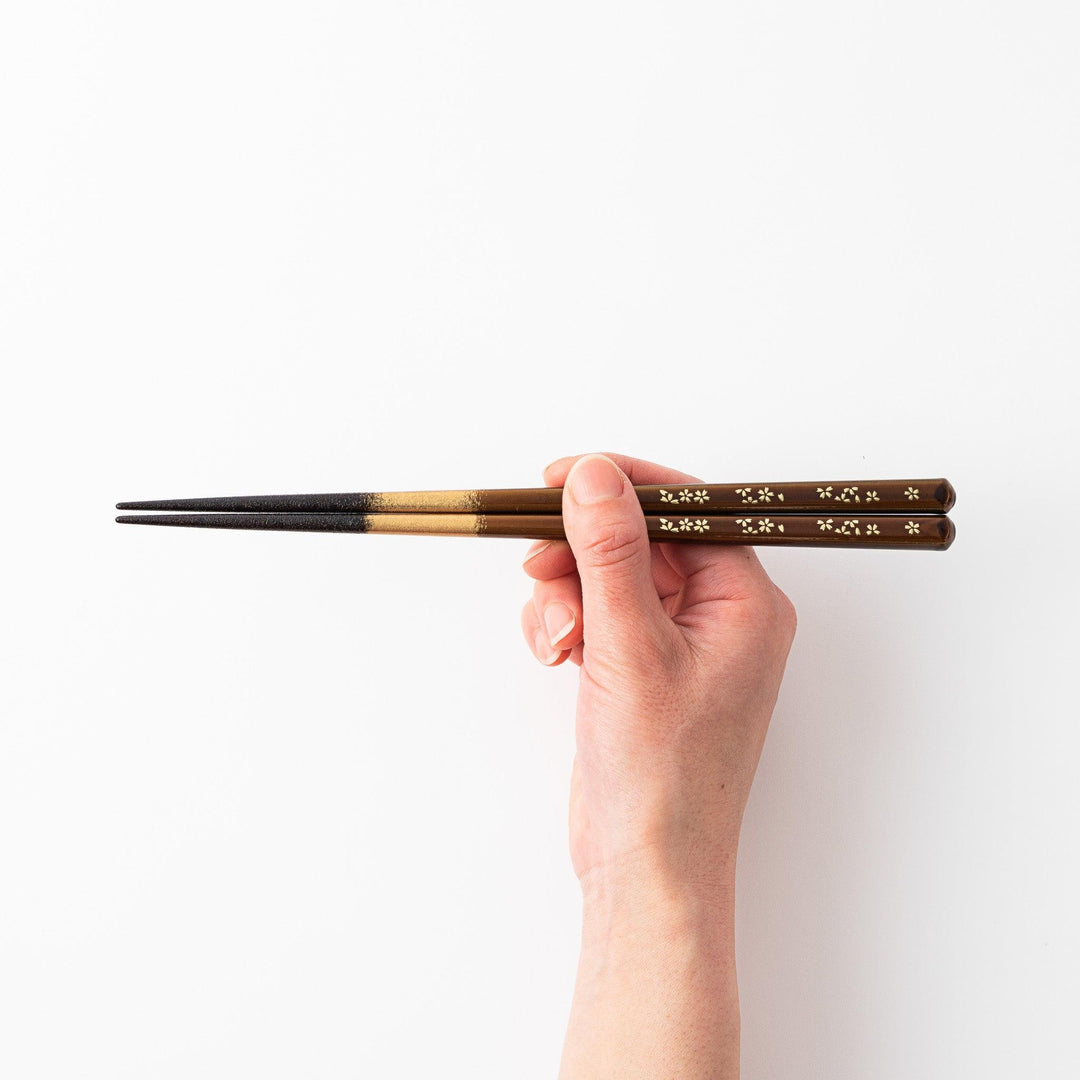 Elegant red and brown lacquered chopsticks adorned with delicate gold cherry blossom motifs, featuring a gradient of gold for added sophistication.