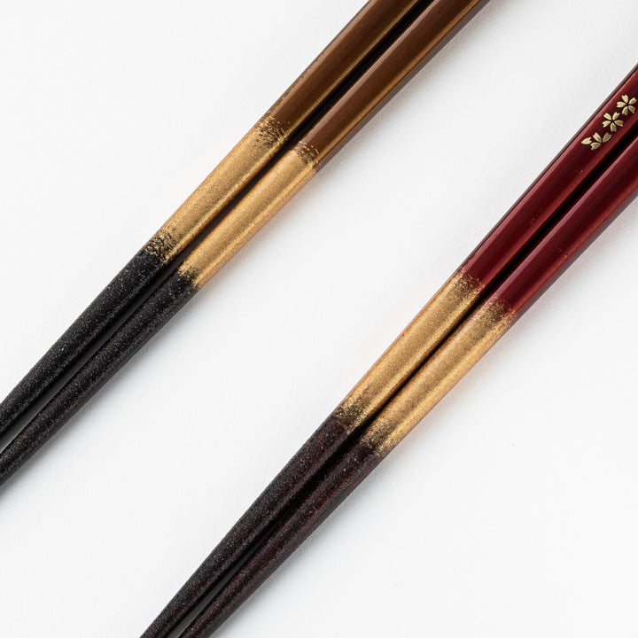 Elegant red and brown lacquered chopsticks adorned with delicate gold cherry blossom motifs, featuring a gradient of gold for added sophistication.