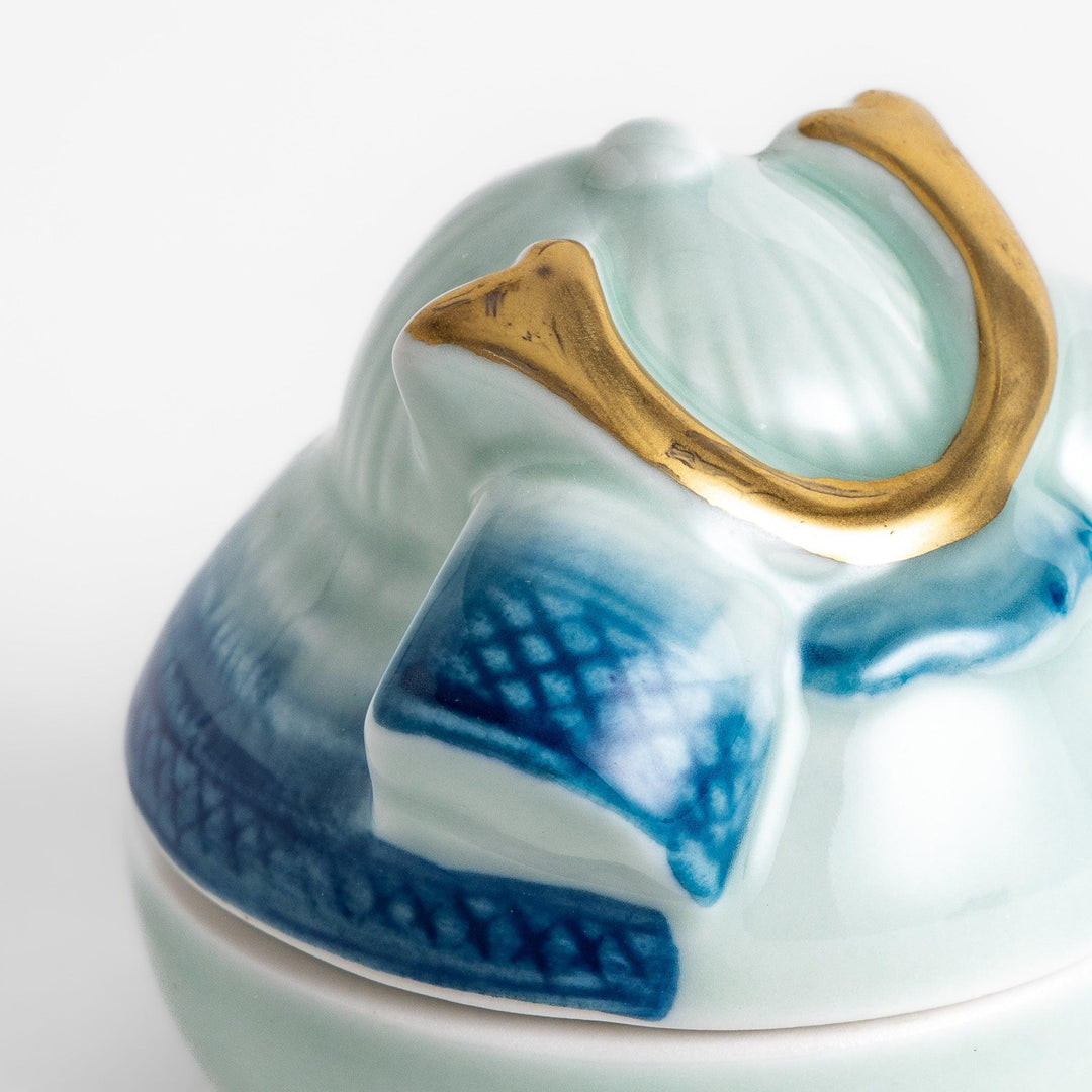 Samurai Helmet Lidded Condiment Bowl, a ceramic bowl with a unique lid shaped like a samurai helmet, featuring intricate blue and gold detailing, perfect for serving sauces.