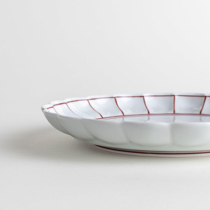 White salad plate with scalloped edges, outlined in a thin blue or red line.