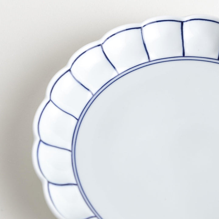 White salad plate with scalloped edges, outlined in a thin blue or red line.
