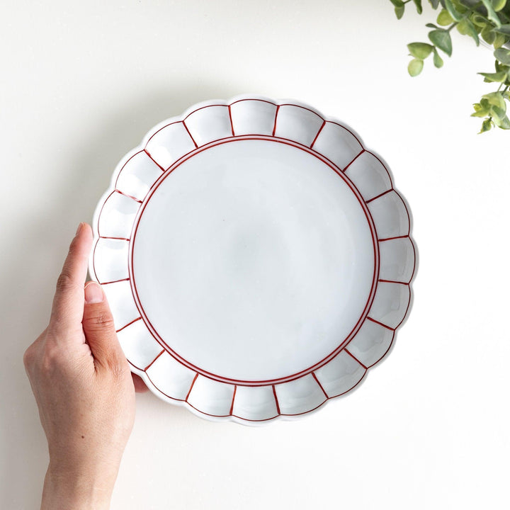 White salad plate with scalloped edges, outlined in a thin blue or red line.