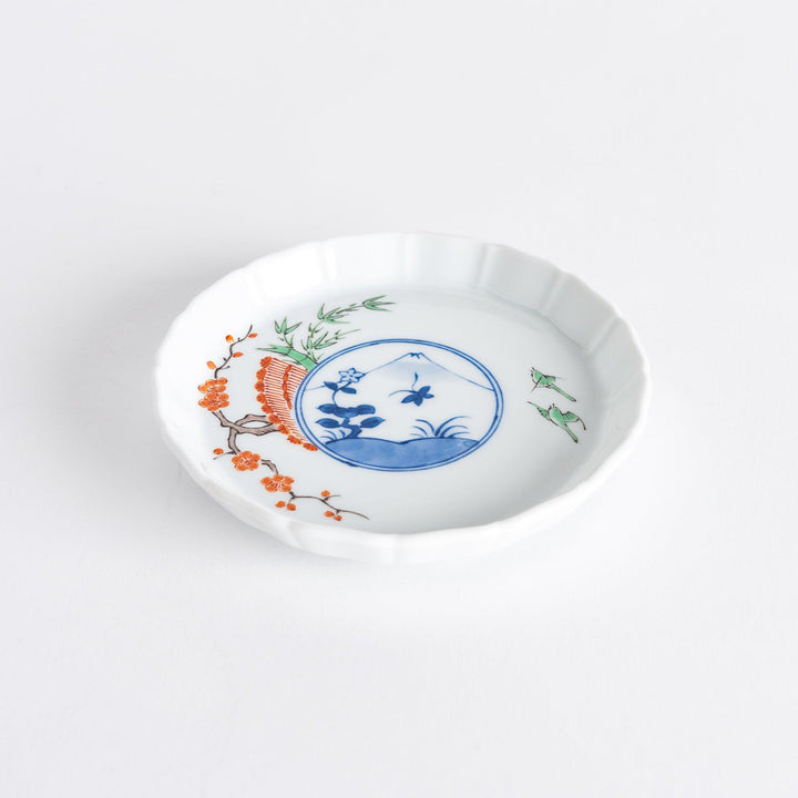 A small round plate with a traditional Japanese design depicting a landscape and floral elements.