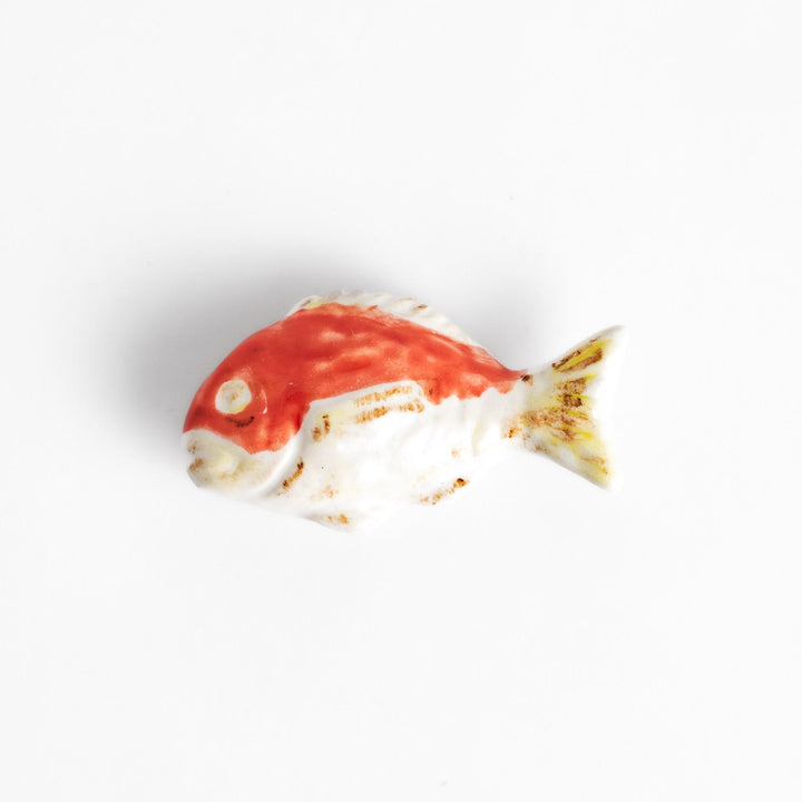 Chopstick rest shaped like a sea bream, intricately painted with red and white hues.