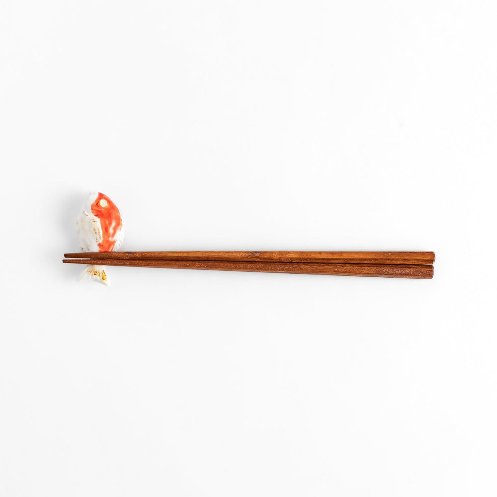 Chopstick rest shaped like a sea bream, intricately painted with red and white hues.