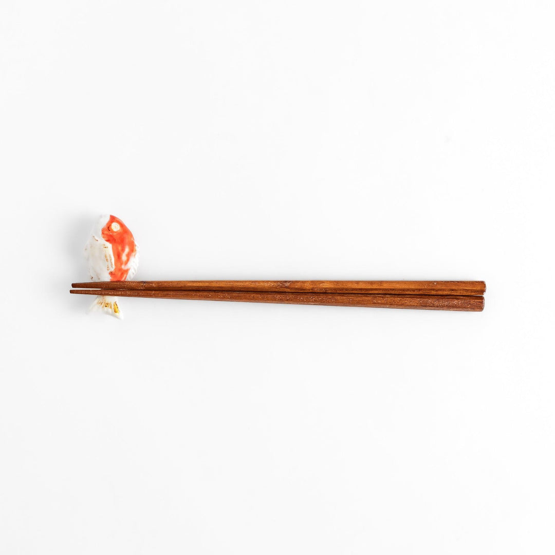 Chopstick rest shaped like a sea bream, intricately painted with red and white hues.