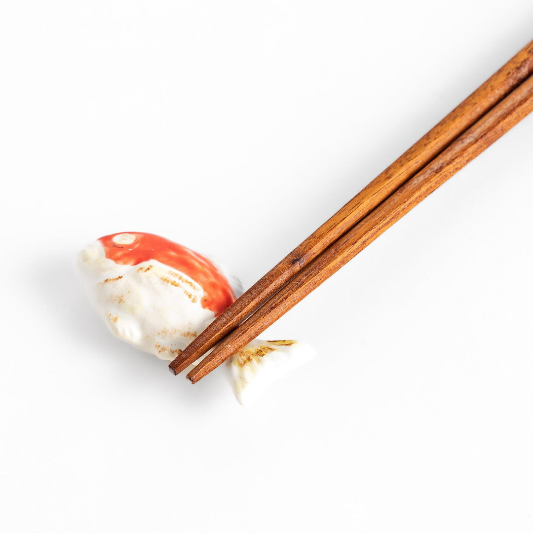 Chopstick rest shaped like a sea bream, intricately painted with red and white hues.