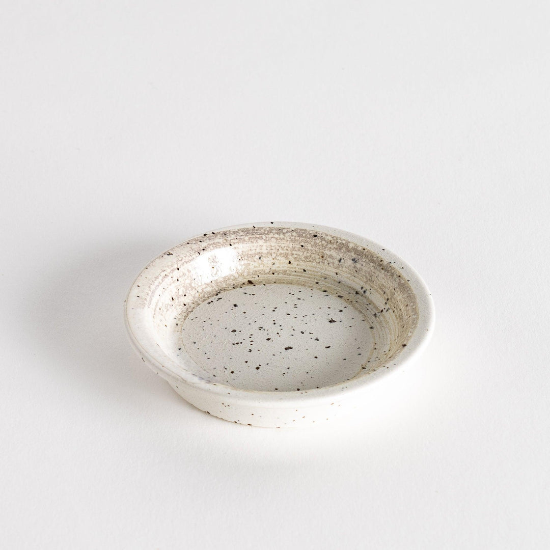 A shallow, off-white dish with a speckled glaze and a slightly textured finish.