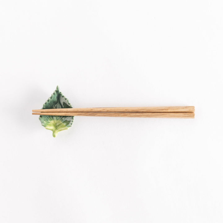 Full view of the shiso leaf chopsticks rest with chopsticks placed across its central ridge.