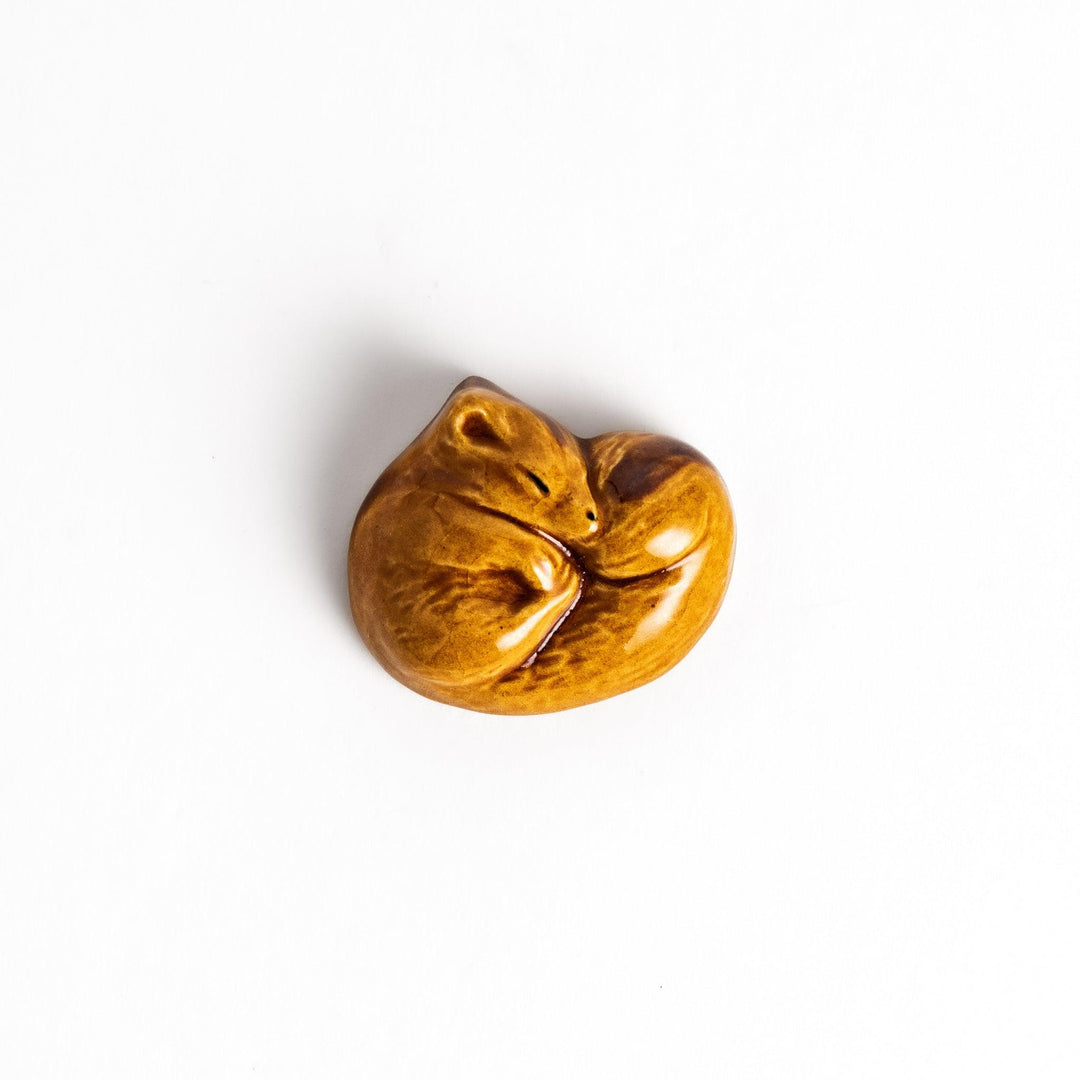 Adorable brown ceramic chopstick rest shaped like a sleeping squirrel, adding a touch of woodland charm to your table setting.