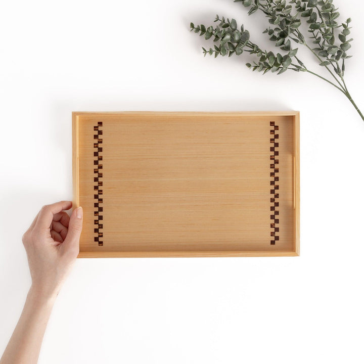 Hand holding a hinoki wood tray with decorative sakura bark accents on the handles, a beautiful and functional serveware piece for any occasion.