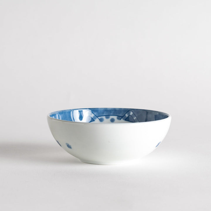 A dessert bowl with a chubby blue-spotted cat, looking peaceful and content.