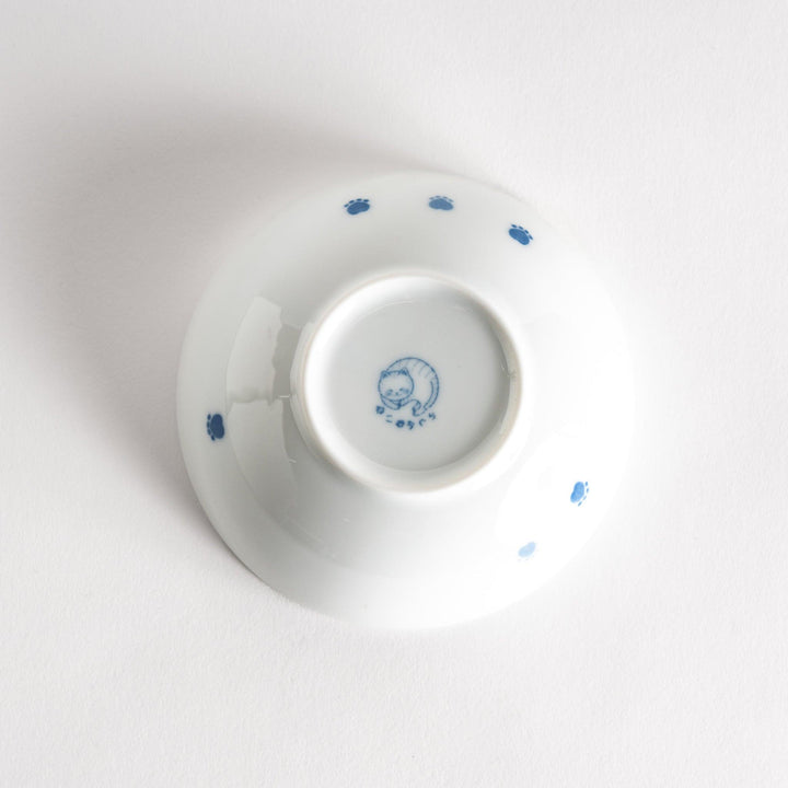 A dessert bowl with a chubby blue-spotted cat, looking peaceful and content.