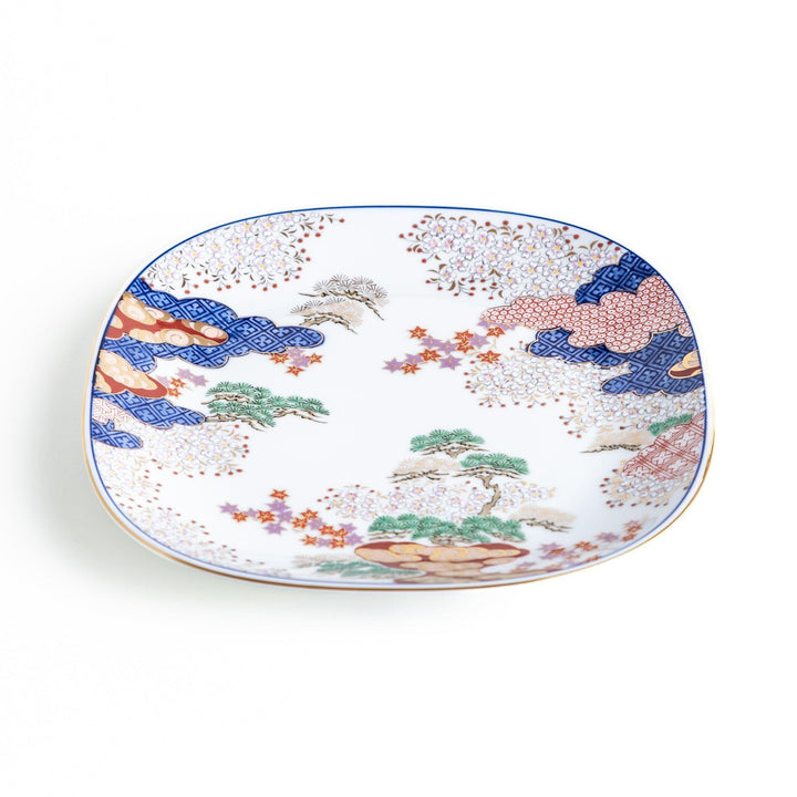 A square salad plate featuring a traditional Japanese landscape with trees, clouds, and maple leaves, framed by intricate blue and red patterns.