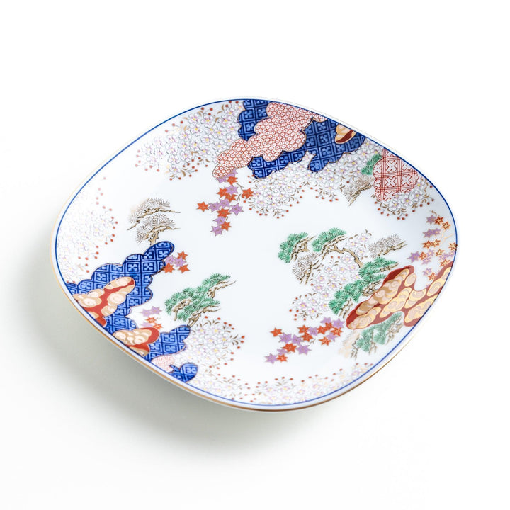 A square salad plate featuring a traditional Japanese landscape with trees, clouds, and maple leaves, framed by intricate blue and red patterns.