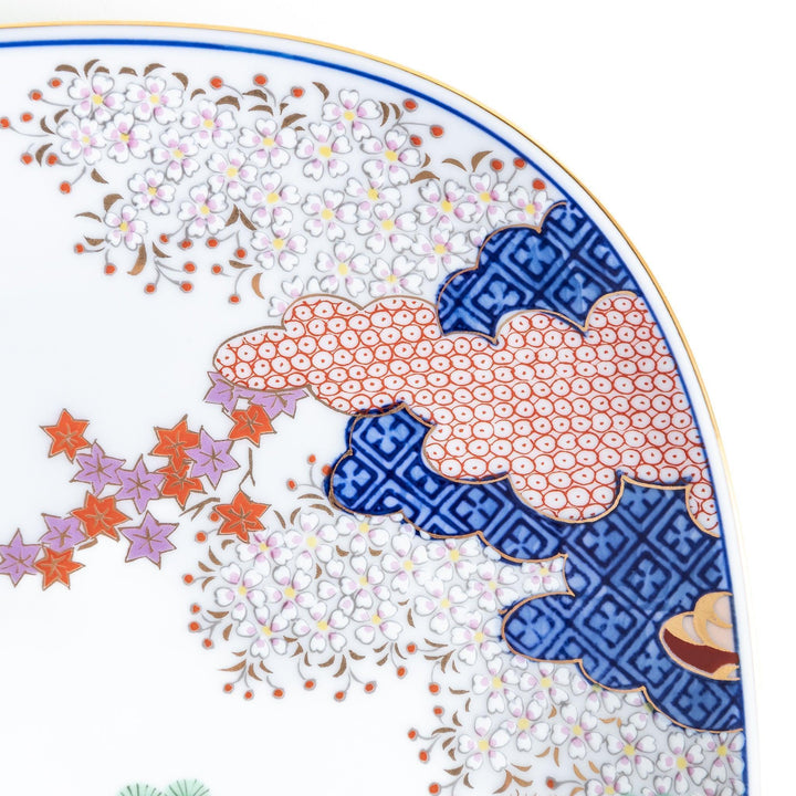 A square salad plate featuring a traditional Japanese landscape with trees, clouds, and maple leaves, framed by intricate blue and red patterns.