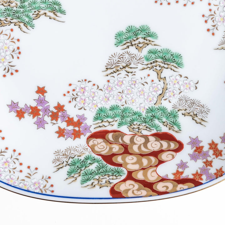 A square salad plate featuring a traditional Japanese landscape with trees, clouds, and maple leaves, framed by intricate blue and red patterns.