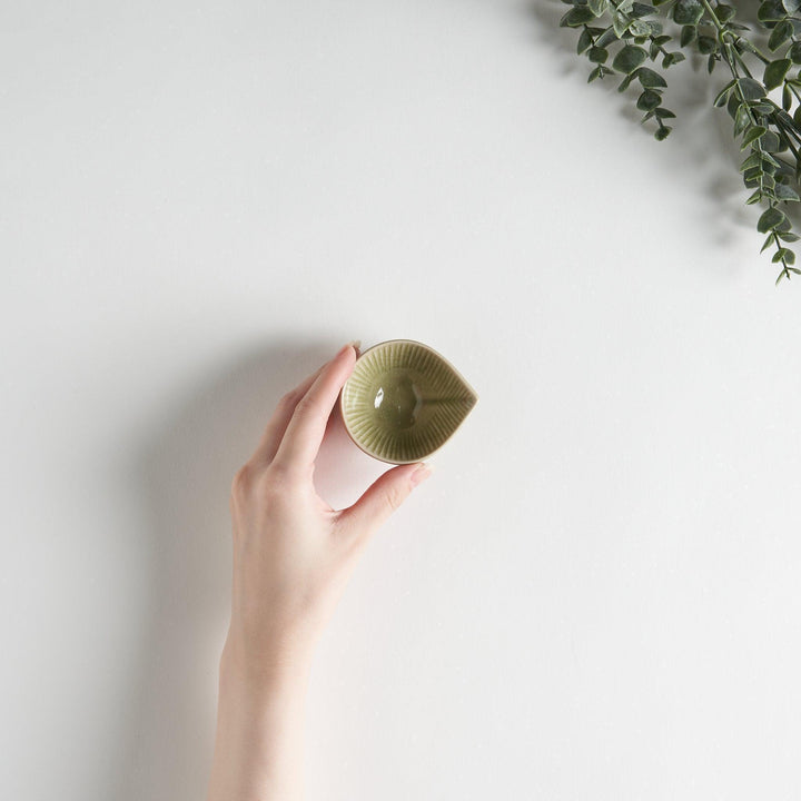 A small condiment bowl with a light green textured surface.