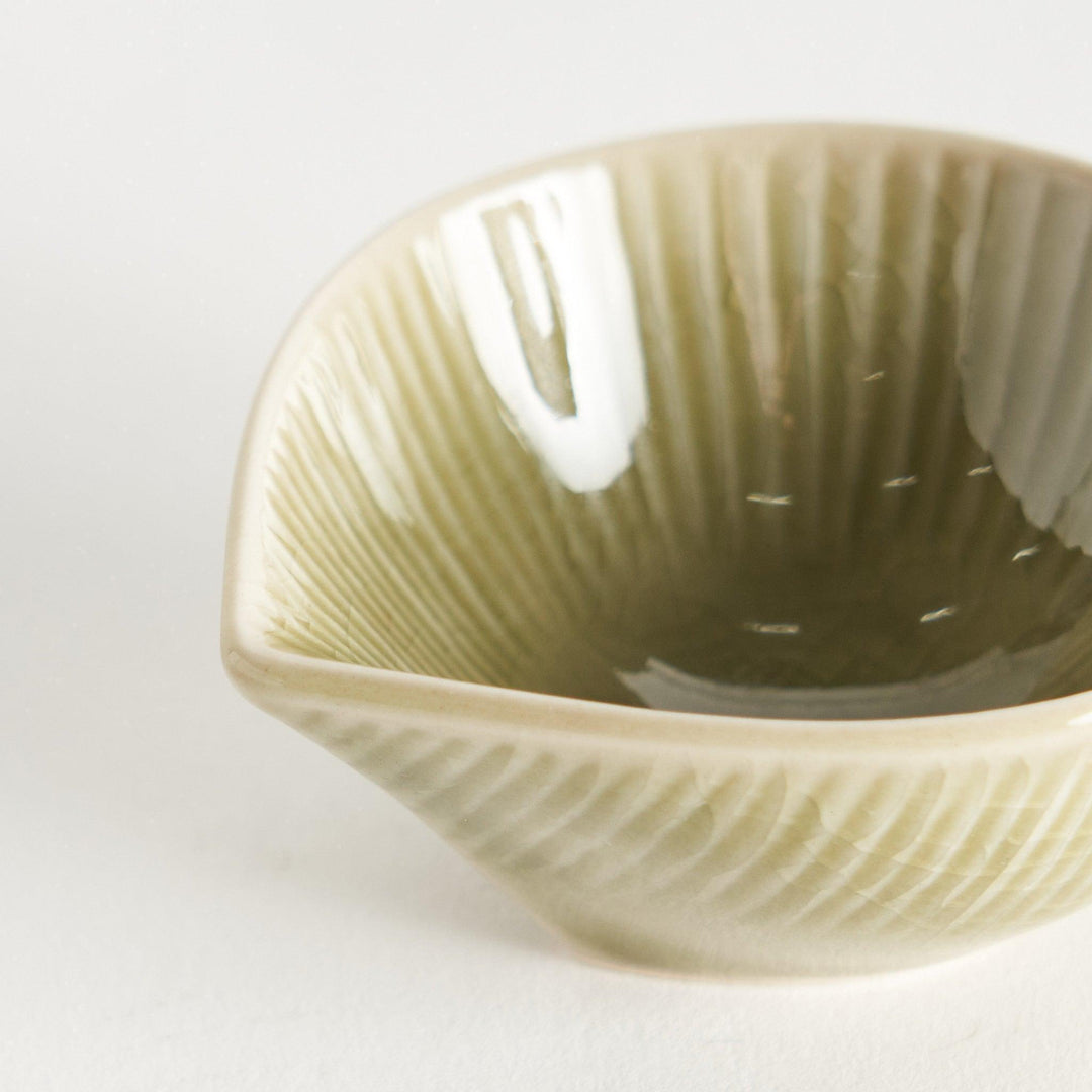 A small condiment bowl with a light green textured surface.