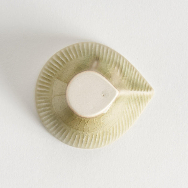 A small condiment bowl with a light green textured surface.