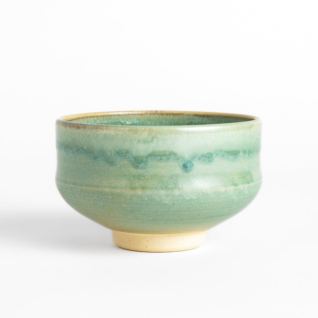 Unique ceramic Matcha bowl with a beautiful green glaze and a rustic base, perfect for enjoying a traditional Japanese tea ceremony.