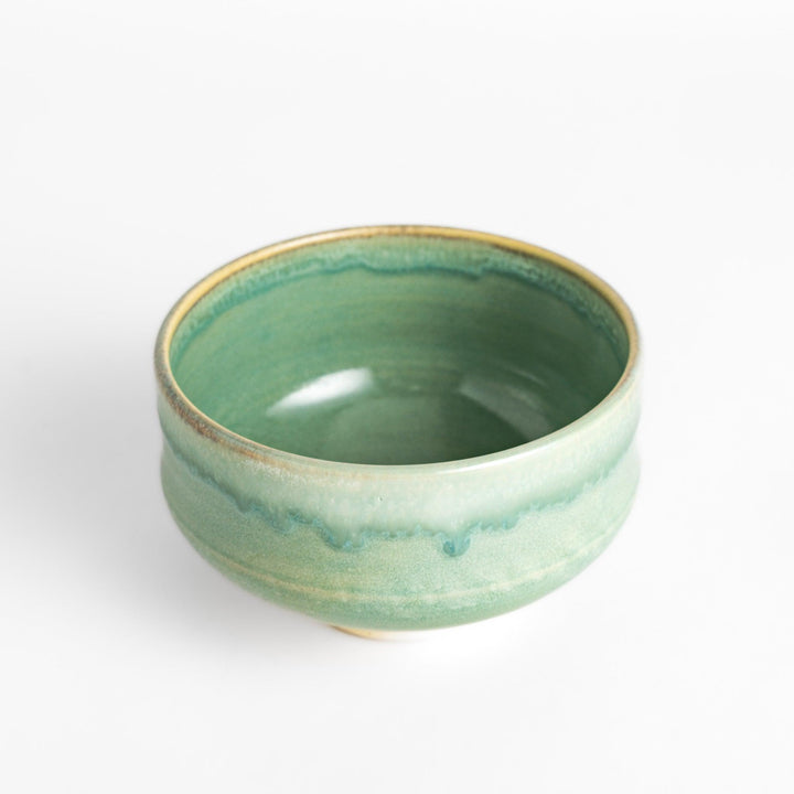 Unique ceramic Matcha bowl with a beautiful green glaze and a rustic base, perfect for enjoying a traditional Japanese tea ceremony.