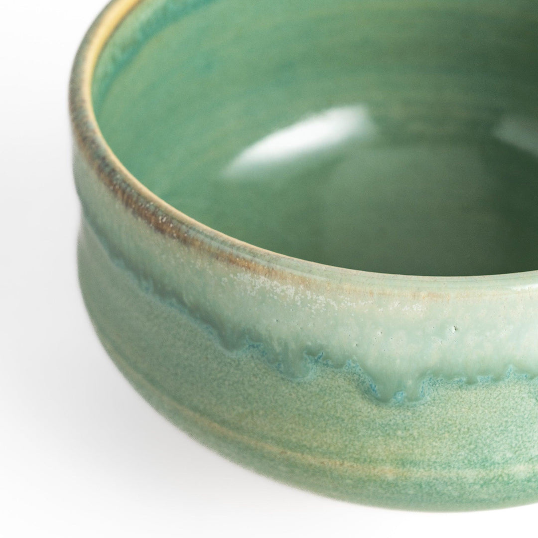 Unique ceramic Matcha bowl with a beautiful green glaze and a rustic base, perfect for enjoying a traditional Japanese tea ceremony.