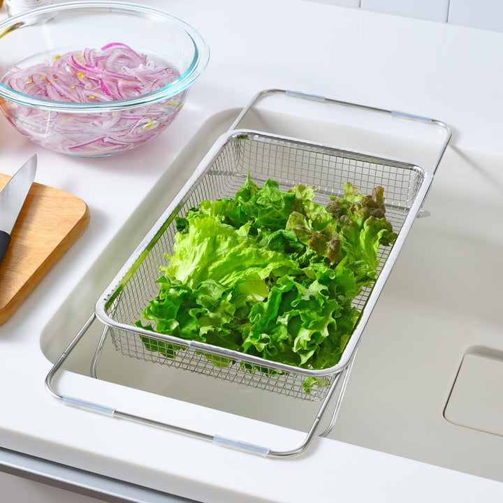 Durable stainless steel draining basket with a fine mesh design, perfect for draining liquids from food during preparation or cooking.