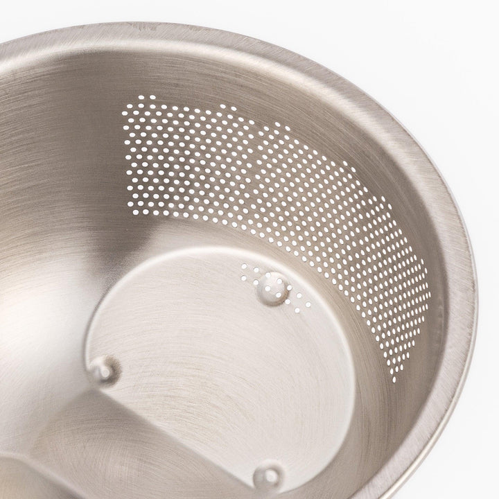 Stainless steel rice washing bowl viewed from above, featuring dual drainage sections—perforated and slotted—for quick, efficient rinsing.