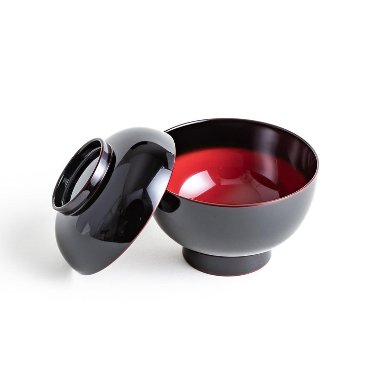 Traditional black lacquer bowl with red interior, featuring a gold pine tree design on the lid.