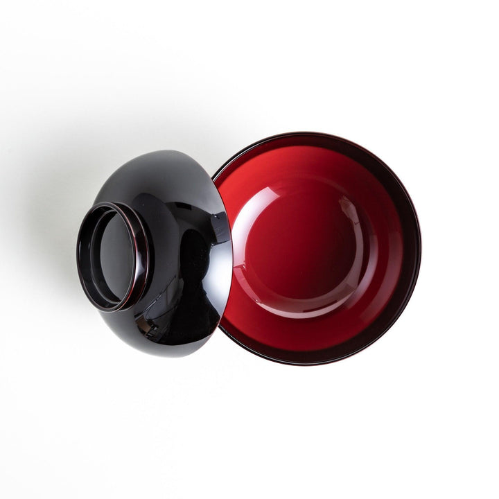 Traditional black lacquer bowl with red interior, featuring a gold pine tree design on the lid.