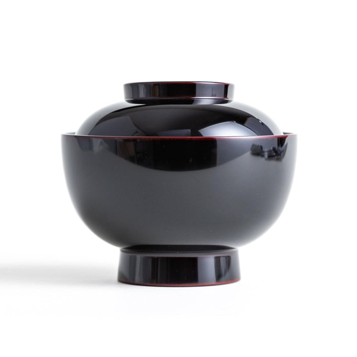 Traditional black lacquer bowl with red interior, featuring a gold pine tree design on the lid.