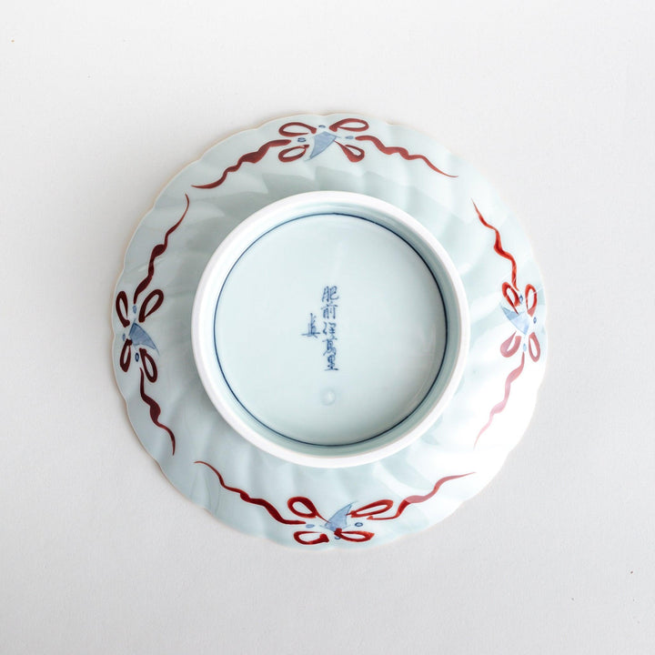 A deep porcelain bowl with an intricate Imari-style design, featuring a central landscape scene and alternating floral patterns in red, blue, and gold.