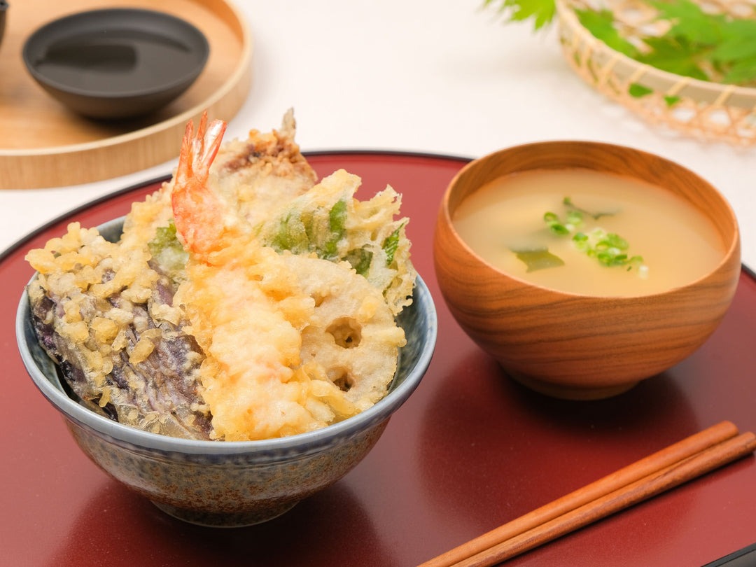 Tendon rice bowl with shrimp tempura served in a rustic Japanese stoneware donburi bowl on a red lacquer tray