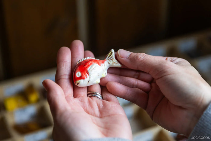a person holding fish chopsticks rest