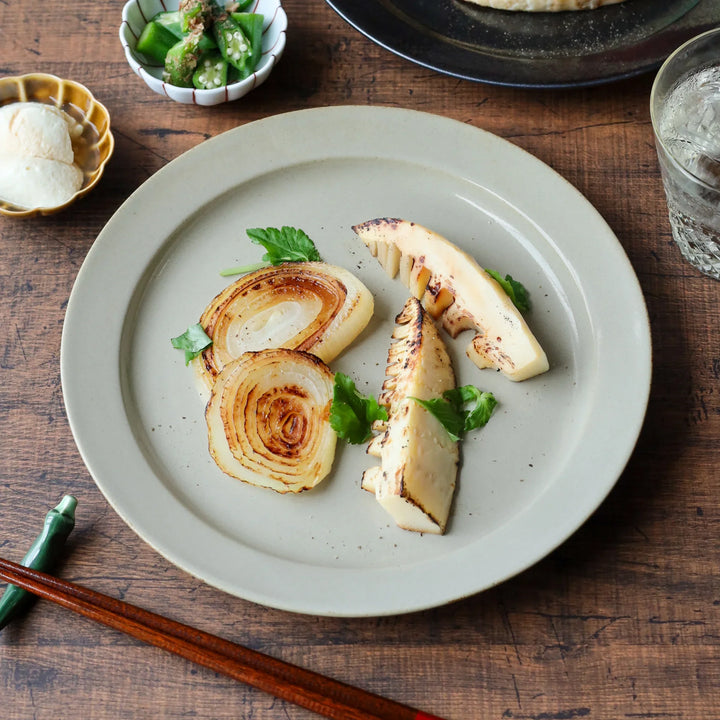 Grilled bamboo shoots and onions arranged on a matte ivory-white Japanese pottery dinner plate.