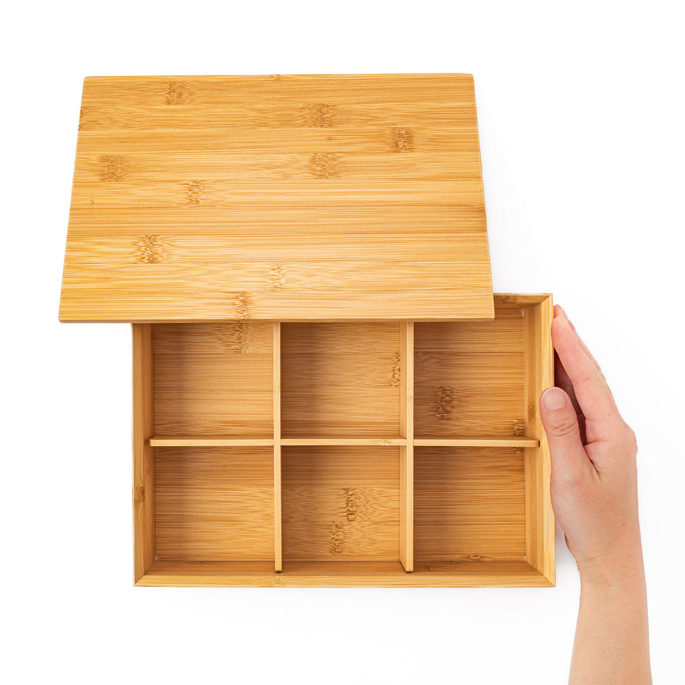Top down view of an open bamboo bento box with a hand revealing six equal inner compartments for perfect food portioning
