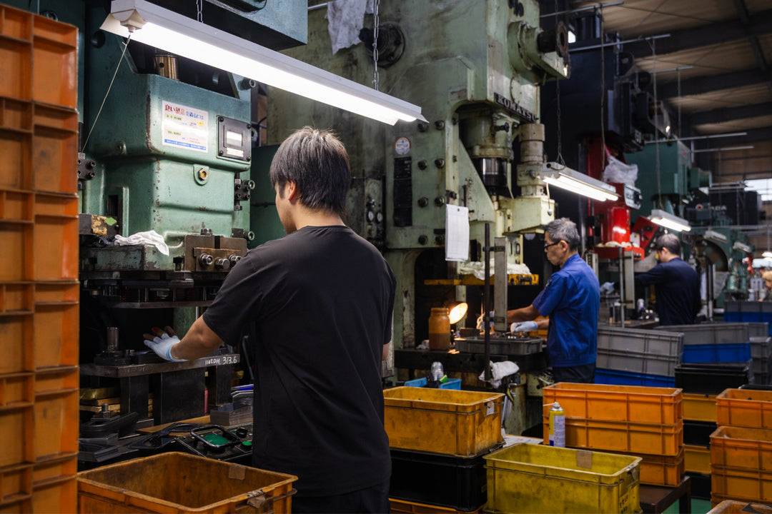 Workers operating large metal presses inside a factory, assembling stainless steel tools in an industrial workshop.