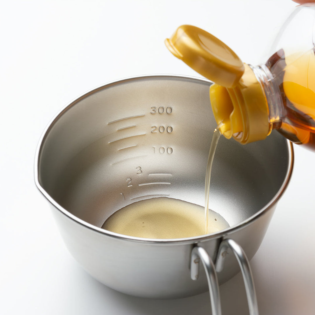 Liquid seasoning being poured into a stainless steel egg beating bowl showing clear interior measurement markings