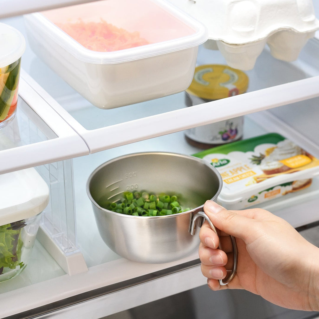 Person placing an AUX Japanese Mini Measuring Bowl with Handle filled with chopped scallions into a refrigerator