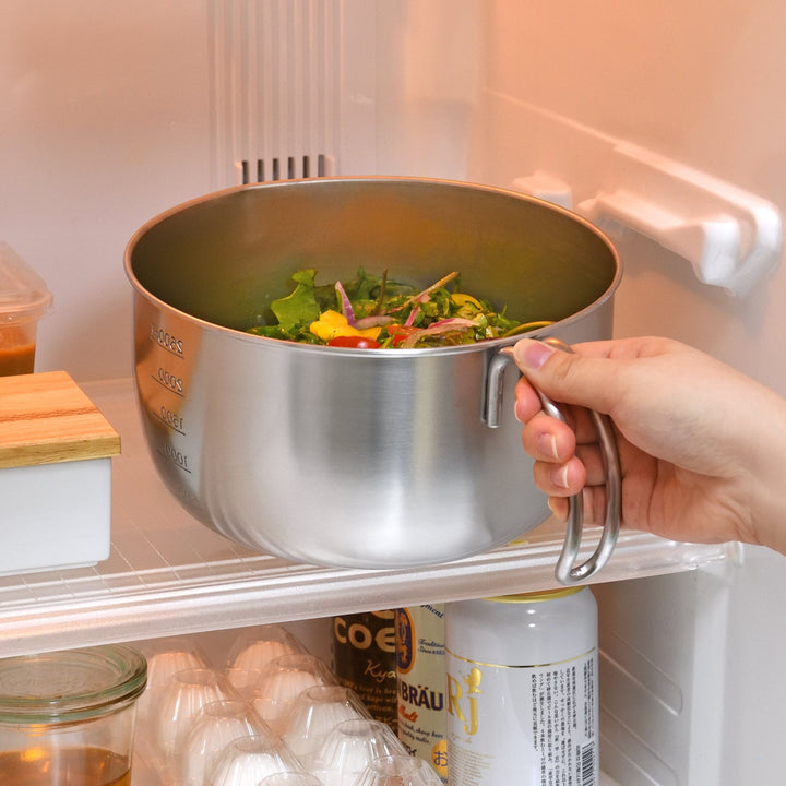 Person placing an AUX Japanese Stainless Steel Mixing Bowl with Handle filled with salad onto a refrigerator shelf
